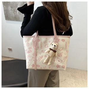 Close-up of printed tote bag with pink leather handles and cute bear charm detail