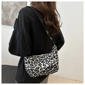 Detail view of leopard print shoulder bag with adjustable black strap and gold buckle