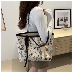 Detail of white PU tote bag with black graffiti print and cute bear plush charm