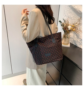 Dettaglio borsa shopper nera con cuori rossi, pizzo decorativo e manici in pelle