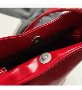 Detail of silver magnetic buckle and glossy red leather interior on a bucket bag