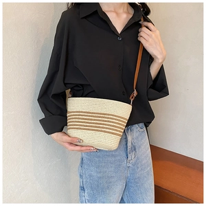 Striped straw bucket bag for summer with brown leather shoulder strap shown on model