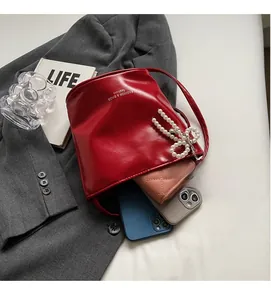 Macro view of a red bucket bag with pearl bow charm and spacious fashion interior