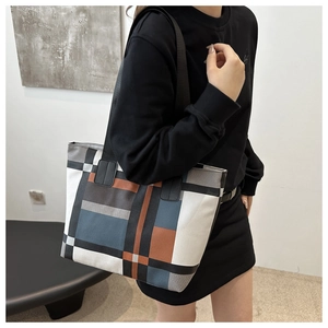 Model wearing a large geometric color-block canvas tote bag with black wide straps