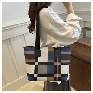 Detail of a large capacity tote bag featuring a geometric patchwork pattern and sturdy straps