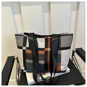 Macro shot of large canvas tote bag featuring modern color-block plaid pattern and strap