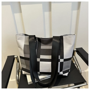 Detail of checkered canvas tote bag with black strap on a minimalist chair