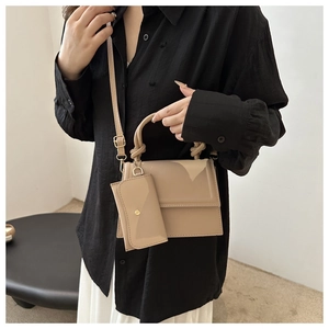 Detail of khaki patent leather handbag with braided handle and gold hardware