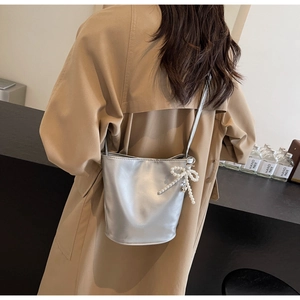 Detail der silbernen Beuteltasche mit Perlen-Schleife und modischem Fashion-Schriftzug