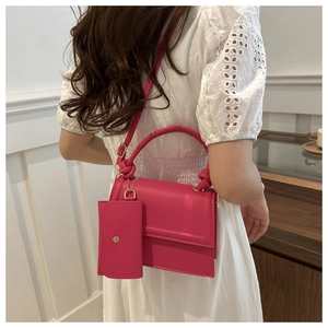 Detail of rose pink crossbody bag with woven handle and small hanging coin purse pouch