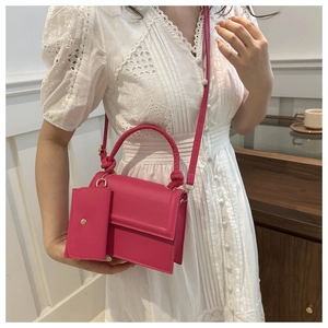 Bright pink mini square bag with knotted handle and matching coin purse on model