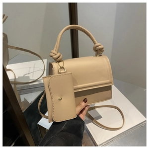 Detail of beige faux leather square handbag with knotted handle and matching coin purse