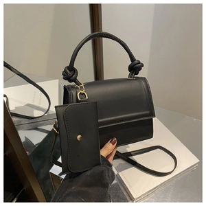 Detail of black crossbody bag with knot handle, gold hardware and matching coin pouch