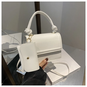 Detail of white rectangular crossbody bag with rope-knot handle and small coin purse attachment