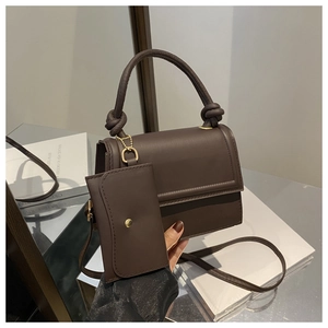 Detailed view of brown leather square handbag with top handle and mini pouch attachment