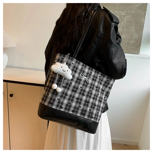 Detail shot of black and white checkered tote bag with silver bow charm and plush cloud