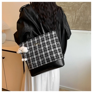 Detail of checkered tote bag with golden bow and cute plush cloud charm on the side