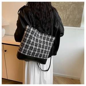 Detail view of black and white checkered backpack with bow accents shown on female model