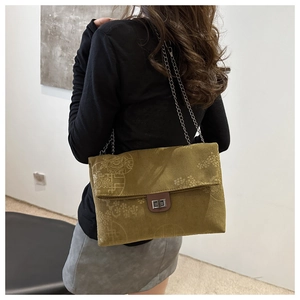 Detail of olive green corduroy shoulder bag featuring embossed floral pattern and chain