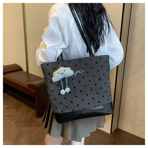 Polka dot tote bag with a white plush cloud charm shown in a cozy indoor setting