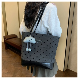 Detail of grey wool tote bag with black polka dots, metallic bow, and cloud charm