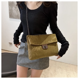 Detail of green corduroy crossbody bag with floral pattern and metal chain on model