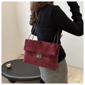 Detail of burgundy corduroy tote bag with traditional embossing and metal chain strap
