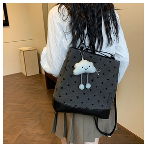 Close-up of gray polka dot backpack with plush cloud charm and leather bottom