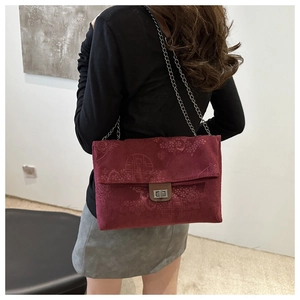 Rear view of a burgundy corduroy tote bag with vintage patterns and silver chain strap