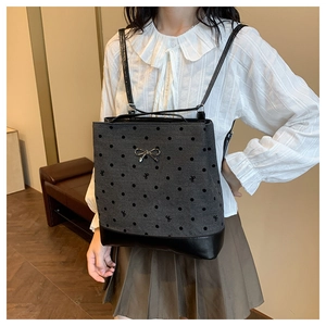 Detail of grey polka dot backpack with silver bow and leather trim on model