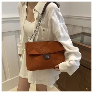 Detail of floral embroidery on corduroy shoulder bag with metal chain strap and twist lock