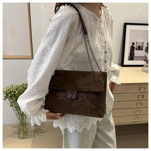 Detailed view of brown corduroy shoulder bag with vintage floral embroidery and chain