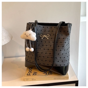 Close-up of gray polka dot tote bag with leather handles on a minimalist book background