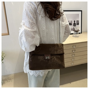 Detail of dark brown corduroy tote bag with floral embroidery and chain strap