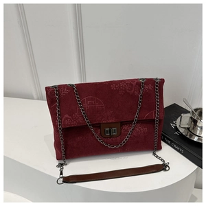 Close-up of deep red corduroy texture with embossed floral patterns and metal chain strap