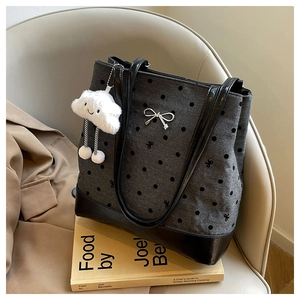 Close-up of charcoal gray polka dot tote bag with metal bow detail and cloud plush charm