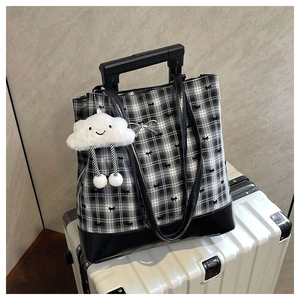 Close-up of checkered tote bag with bow texture and plush cloud charm on suitcase