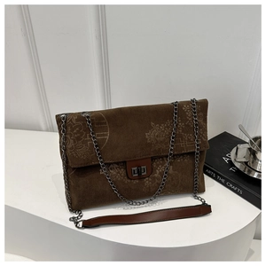 Close-up of dark brown corduroy bag featuring embossed vintage floral patterns and metal lock