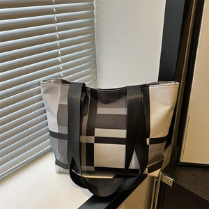 Canvas tote bag with large black and white check pattern and wide nylon shoulder strap