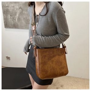 Detail showing vintage brown PU leather texture and wide jacquard woven shoulder strap