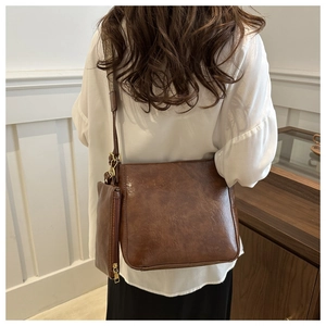 Close-up of retro brown bucket bag with wide strap and small pouch on female model
