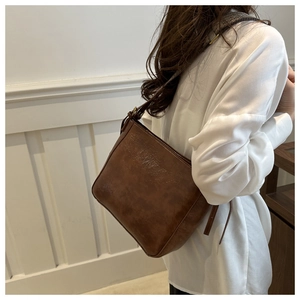 Detail view of retro large brown leather shoulder bag on a white shirt outfit