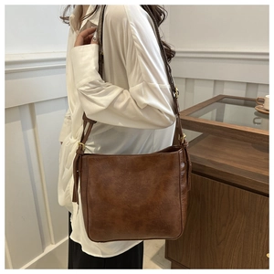 Close-up of vintage brown large capacity shoulder bag with adjustable gold metal buckles
