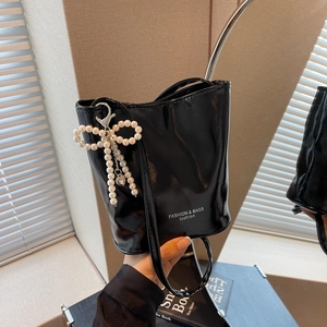 Schicke Eimertasche aus schwarzem Lackleder mit Perlen-Schleifen-Anhänger und Schultergurt