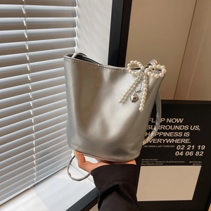 Silberne Beuteltasche mit Perlen-Schleifen-Anhänger und Metallic-Finish für Sommer 2024