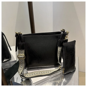 Close-up of black glossy leather bucket bag with bohemian patterned wide shoulder strap