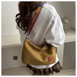 Detailed view of yellow canvas pillow bag with colorful wide strap and leather logo patch