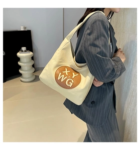 Detail of canvas tote bag with brown leather XY WG patch worn on the shoulder