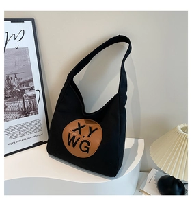 Close-up of black canvas shoulder bag featuring a brown leather embossed XYWG logo patch