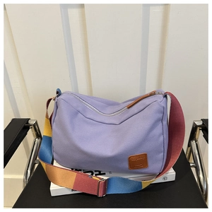 Detail of lavender canvas crossbody bag featuring colorful wide woven shoulder strap